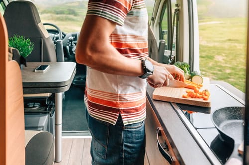 A man cutting vegetables with his RV kitchen essentials
